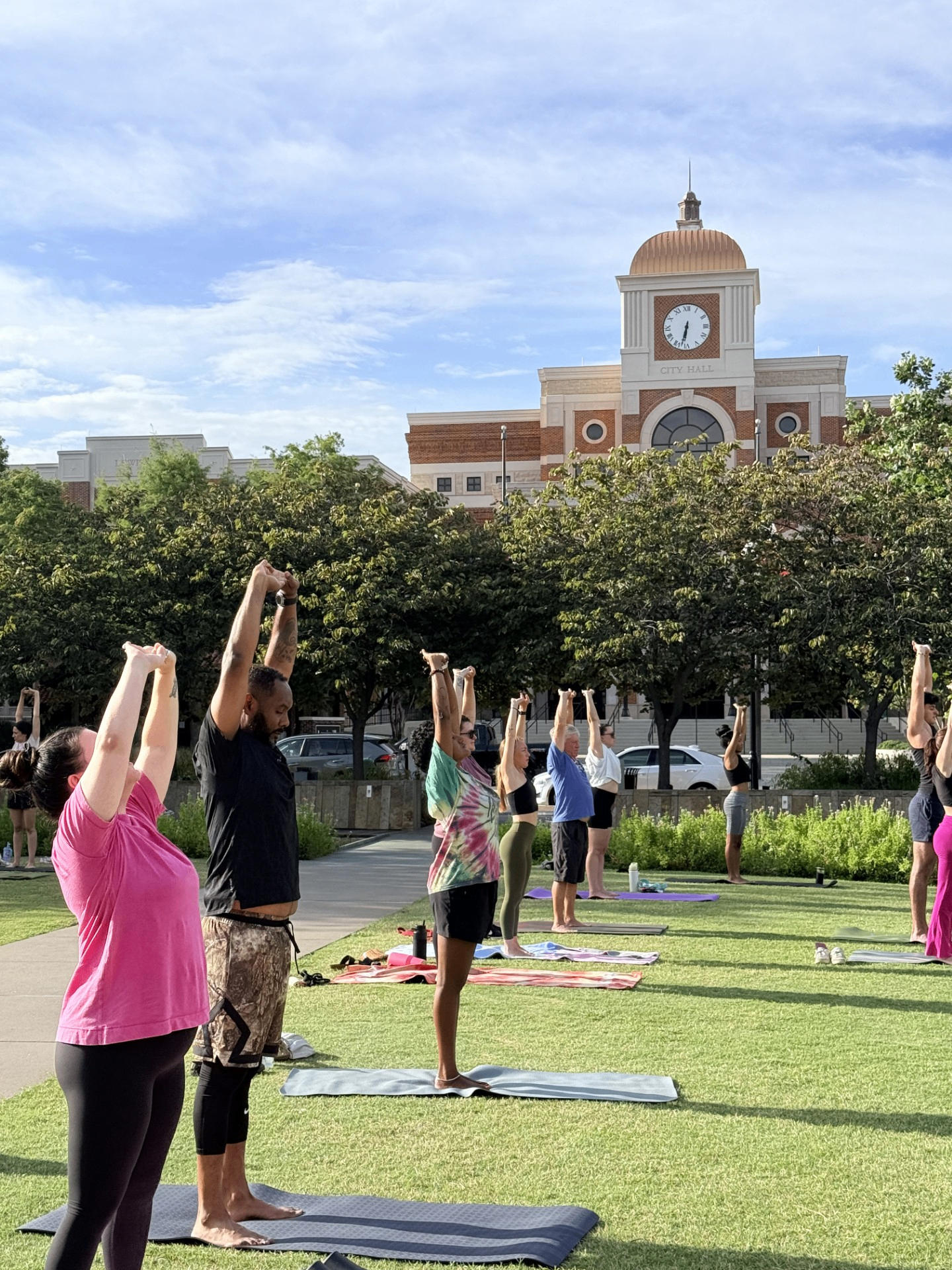 Community members practicing yoga outdoors at Wayne Ferguson Plaza in front of Lewisville City Hall