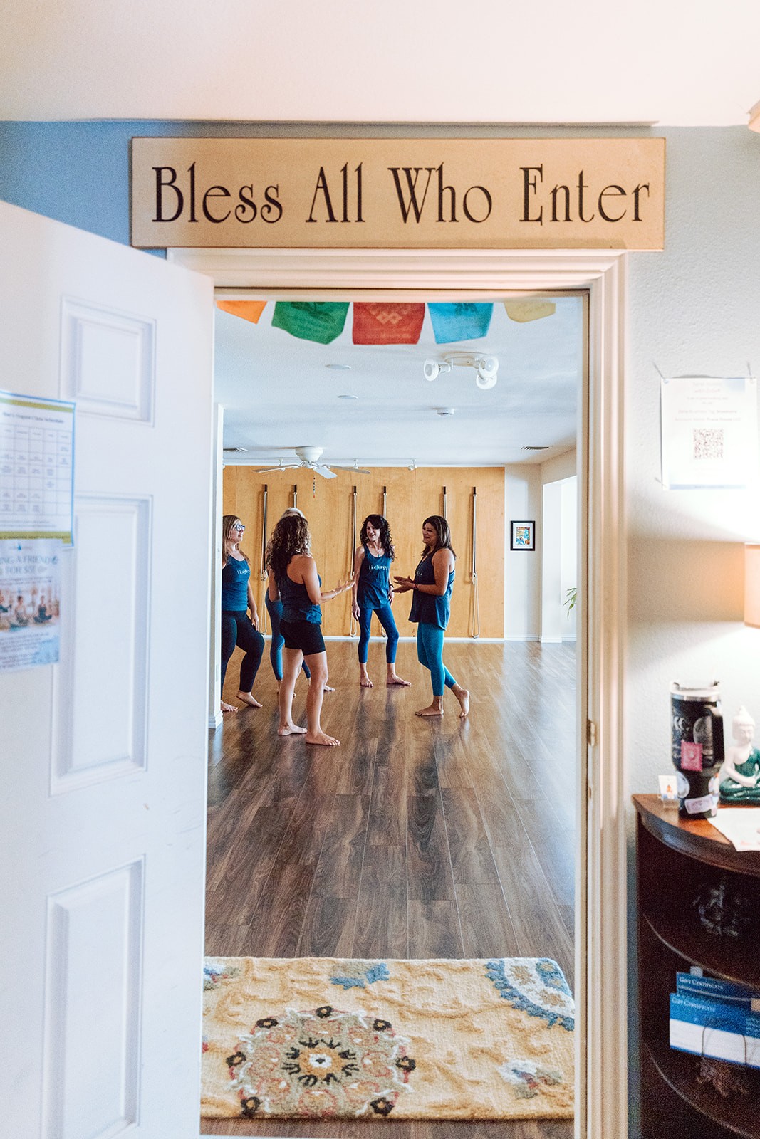 Teachers gathered in the rope wall room beneath a Bless All Who Enter doorway