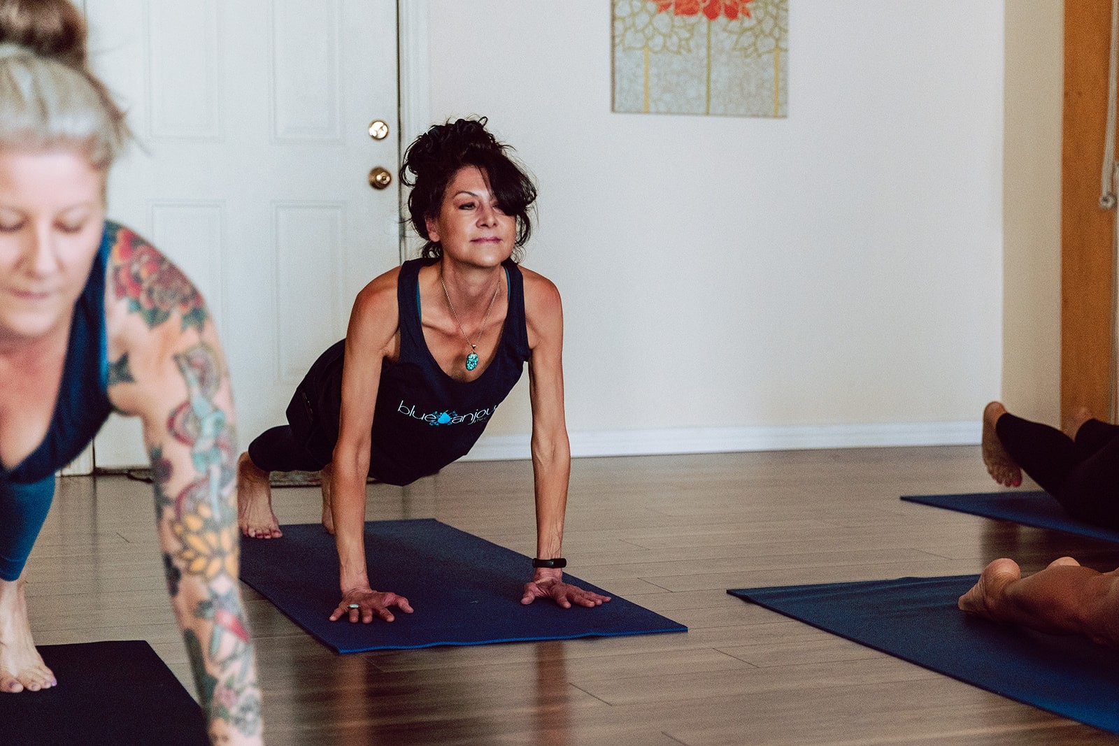 Teacher guiding a class through a low lunge on blue mats