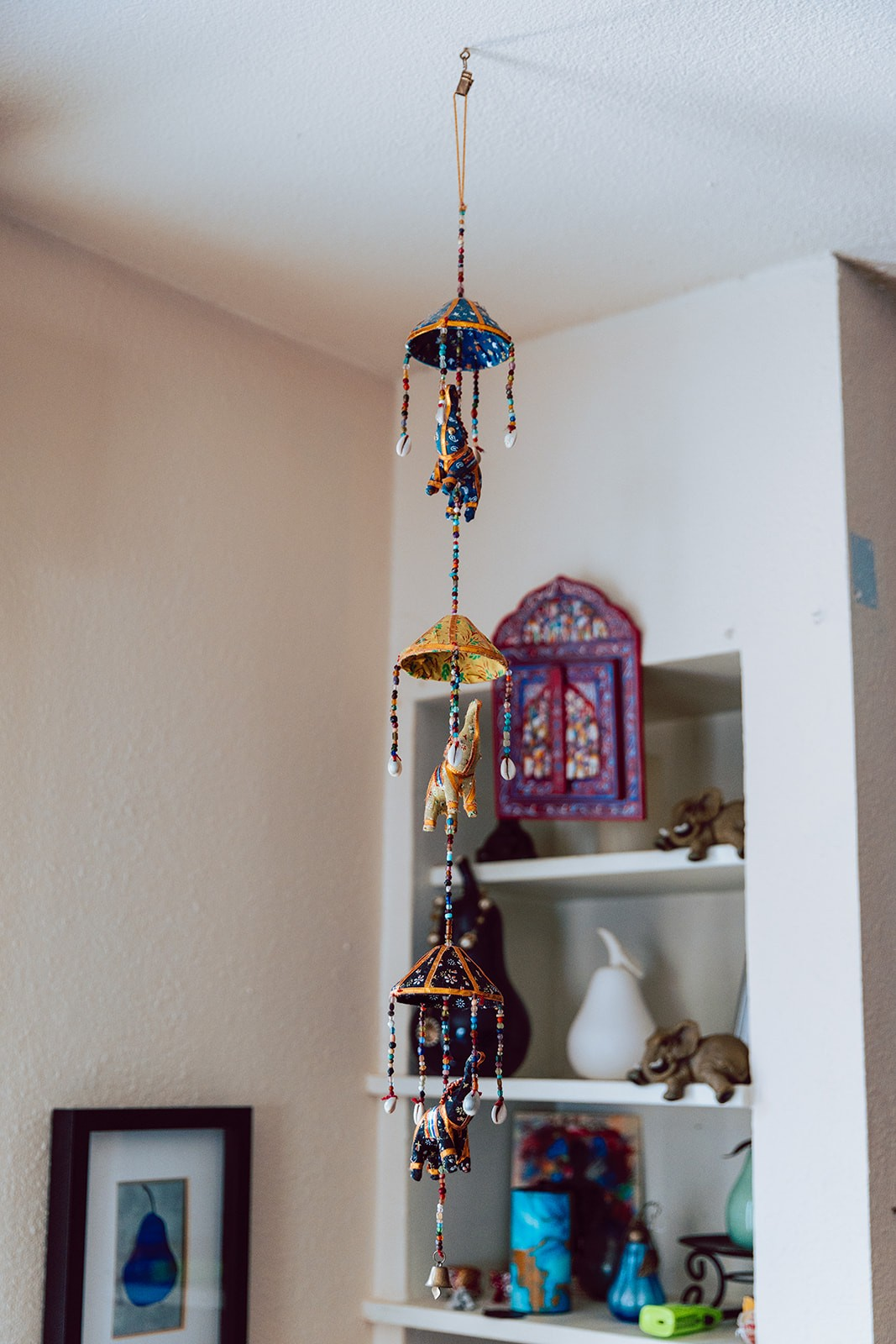 Hand-painted elephant mobile hanging near the studio shelves