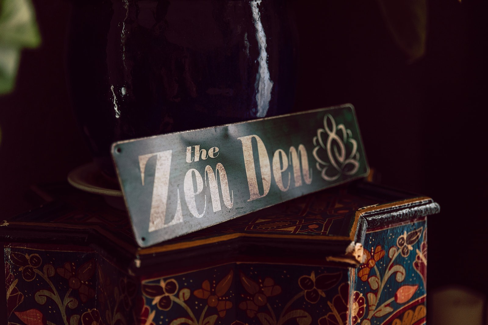 Hand-painted Zen Den sign on a wooden box in the studio